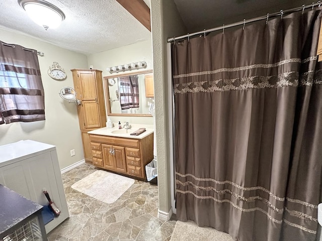 full bath with a shower with shower curtain, stone finish floor, a textured ceiling, vanity, and baseboards