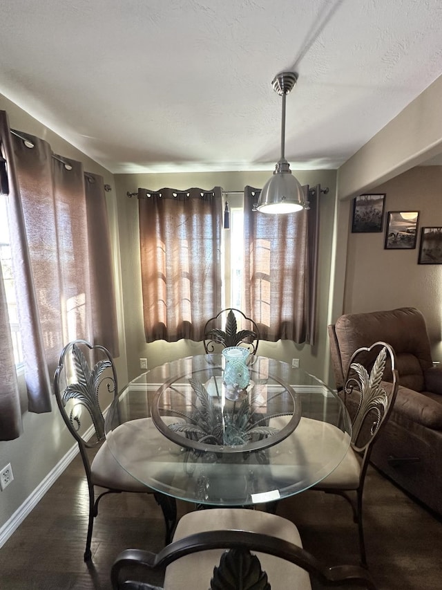 dining room with a textured ceiling, wood finished floors, and baseboards