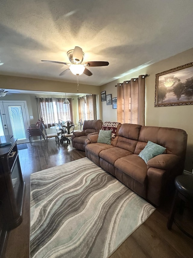 living room with a ceiling fan, wood-type flooring, and a textured ceiling