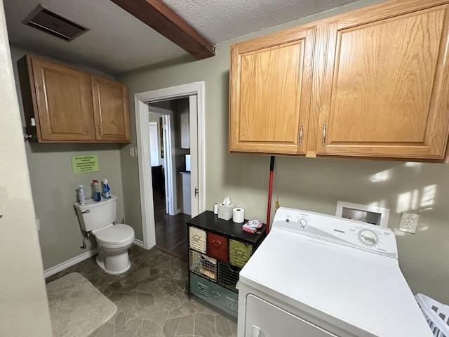 clothes washing area with washer / clothes dryer, visible vents, a textured ceiling, laundry area, and baseboards