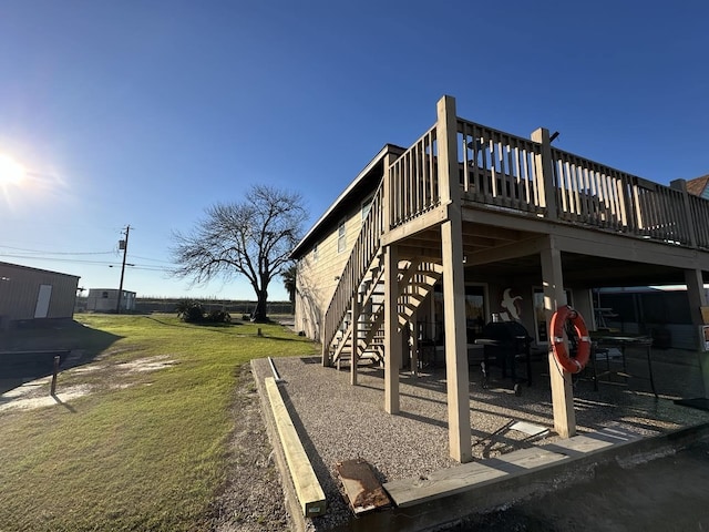 rear view of house with a yard, stairway, and a wooden deck