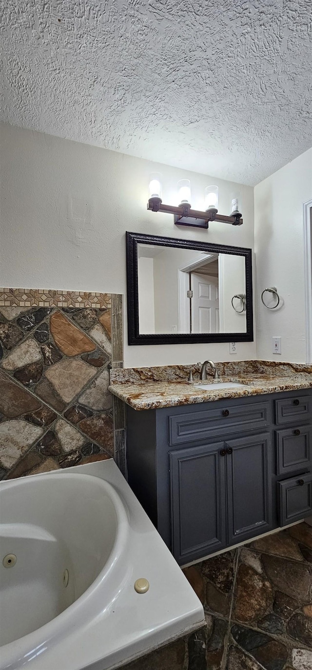 bathroom with a bathing tub, vanity, and a textured ceiling