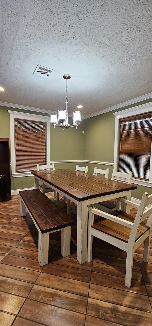 unfurnished dining area featuring a chandelier, a textured ceiling, tile patterned floors, and ornamental molding