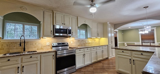 kitchen with sink, stainless steel appliances, tile patterned floors, a textured ceiling, and decorative light fixtures