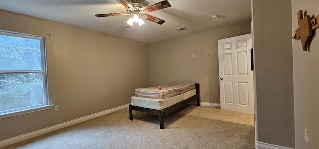 carpeted bedroom with multiple windows, a textured ceiling, and ceiling fan