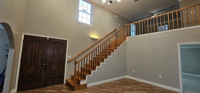 tiled foyer entrance featuring a towering ceiling, a textured ceiling, ceiling fan with notable chandelier, and crown molding