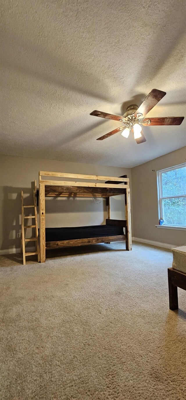 unfurnished bedroom featuring ceiling fan, carpet, and a textured ceiling