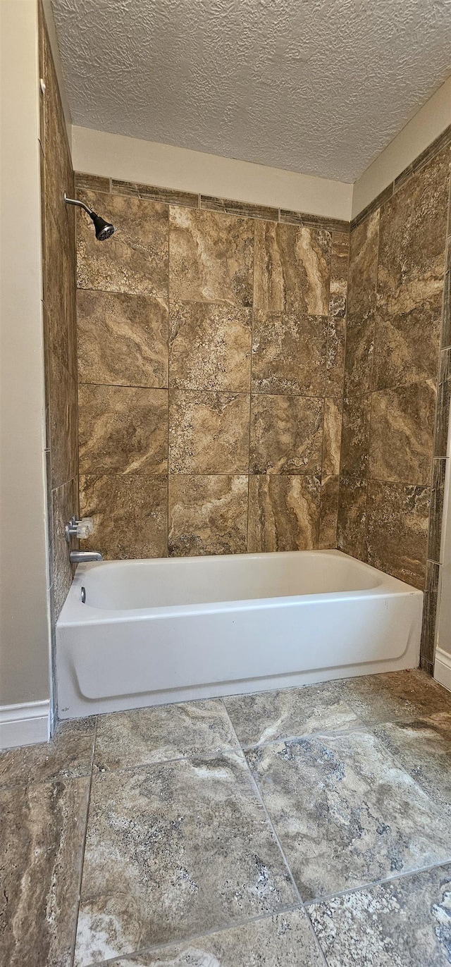 bathroom featuring tiled shower / bath combo and a textured ceiling