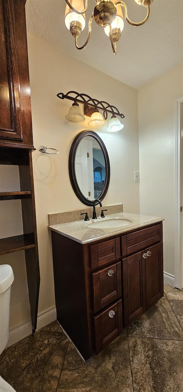 bathroom with vanity, an inviting chandelier, and toilet