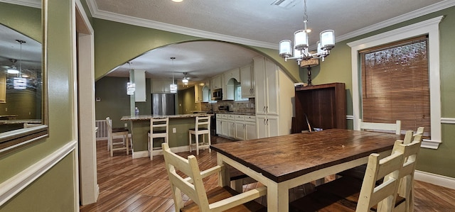 dining area featuring ceiling fan with notable chandelier, ornamental molding, and a textured ceiling