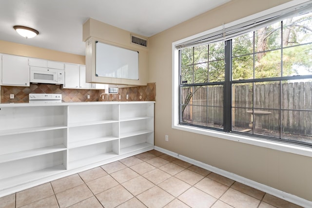 kitchen with decorative backsplash, light tile patterned floors, white cabinets, and white appliances