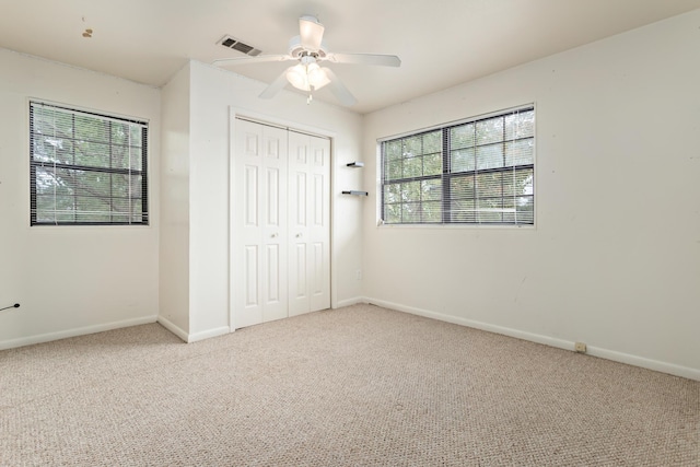 unfurnished bedroom with multiple windows, ceiling fan, a closet, and carpet floors