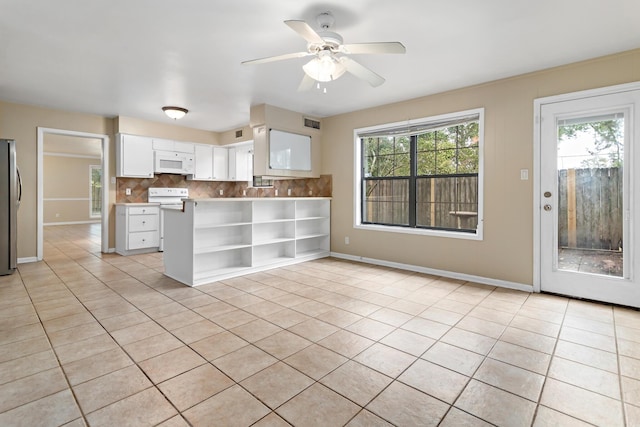 kitchen with stainless steel refrigerator, white cabinetry, light tile patterned floors, and tasteful backsplash