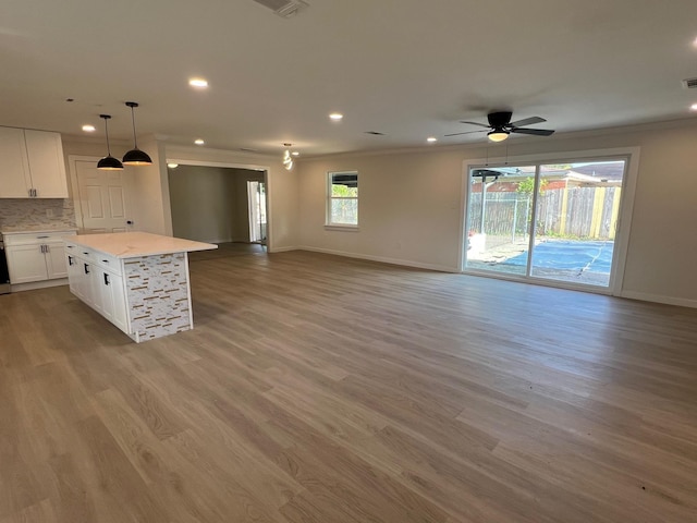 kitchen featuring a kitchen island, white cabinetry, open floor plan, light countertops, and hanging light fixtures