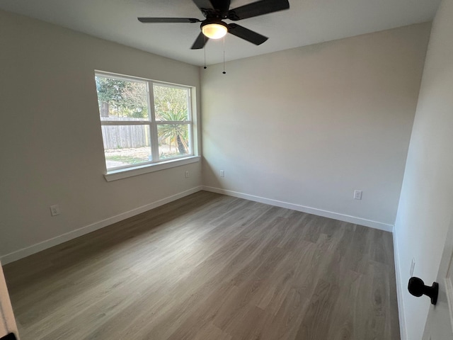 unfurnished room with wood finished floors, a ceiling fan, and baseboards