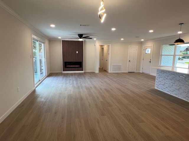 unfurnished living room featuring hardwood / wood-style flooring, crown molding, ceiling fan, and a fireplace