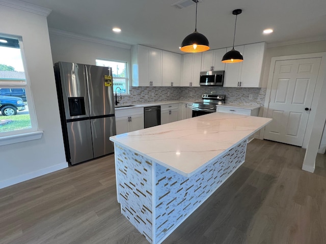 kitchen featuring sink, decorative light fixtures, a center island, stainless steel appliances, and white cabinets