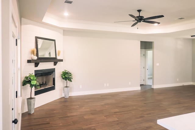 living room with a raised ceiling, dark wood-type flooring, and a fireplace