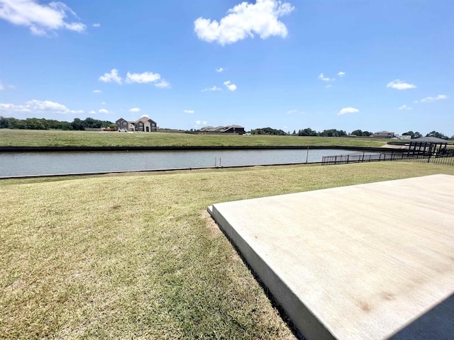 view of property's community with a lawn, a water view, and fence