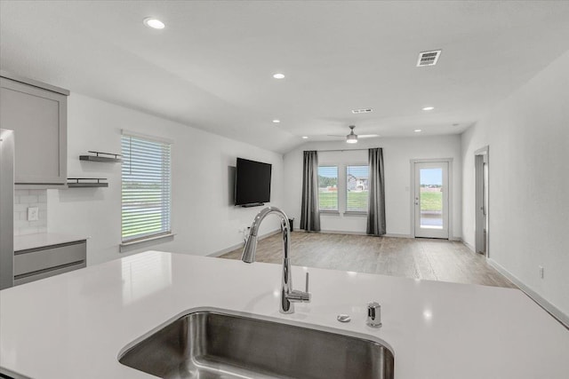 kitchen with light wood finished floors, visible vents, gray cabinets, light countertops, and a sink