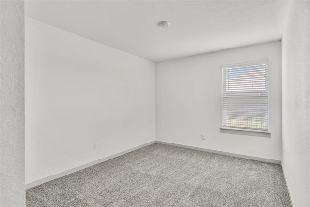 carpeted empty room with baseboards