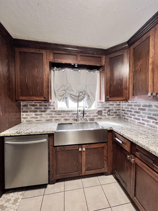 kitchen with light stone counters, stainless steel dishwasher, dark brown cabinets, sink, and light tile patterned floors