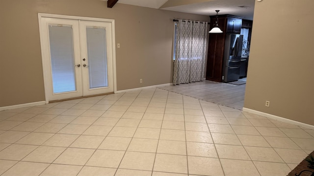 tiled empty room featuring beam ceiling and french doors