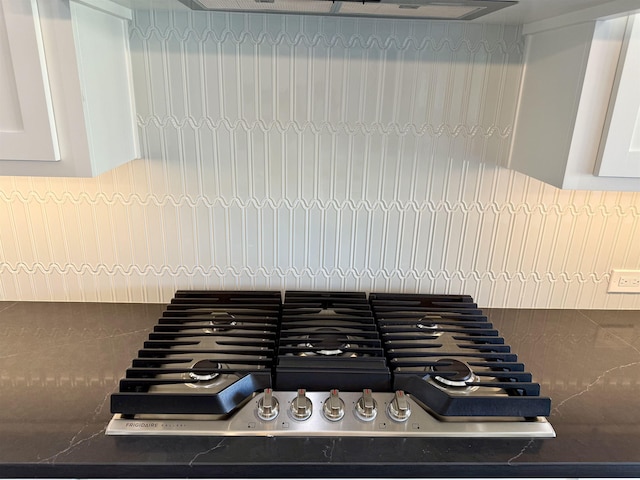 interior details featuring stainless steel gas stovetop, exhaust hood, tasteful backsplash, and white cabinets