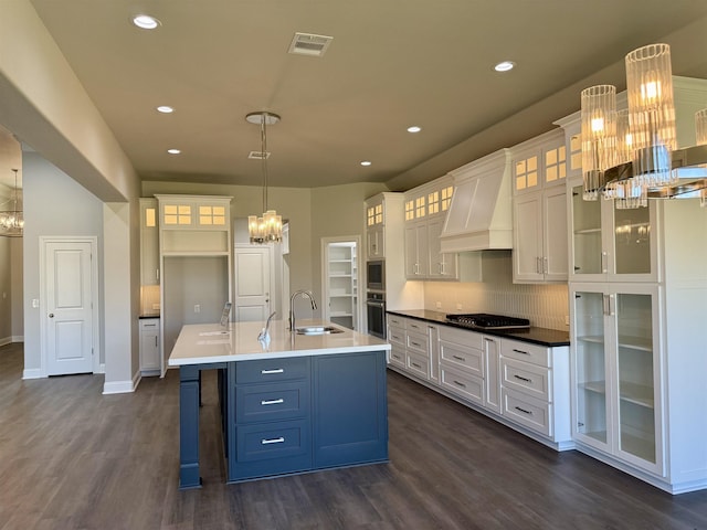 kitchen with a sink, custom exhaust hood, appliances with stainless steel finishes, and a chandelier