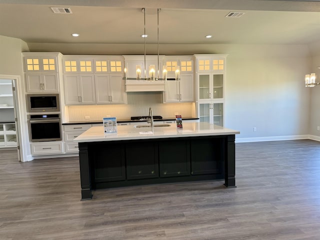 kitchen featuring visible vents, a chandelier, a center island with sink, stainless steel appliances, and white cabinetry