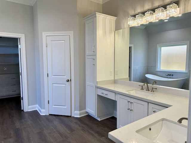 bathroom featuring a soaking tub, vanity, baseboards, and wood finished floors