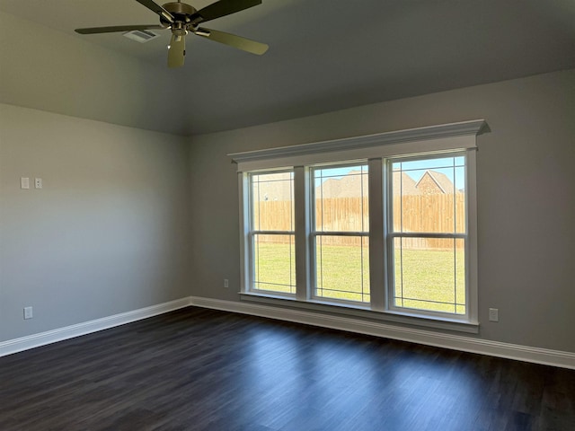 empty room featuring dark wood-style floors, visible vents, baseboards, lofted ceiling, and ceiling fan