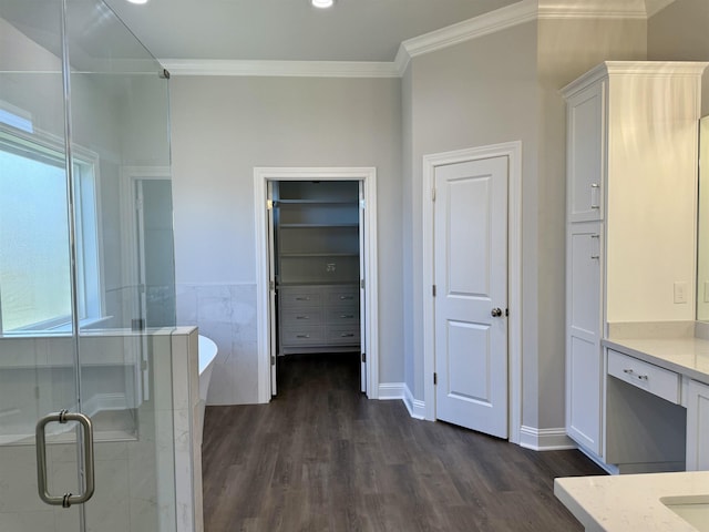 full bathroom featuring wood finished floors, a freestanding tub, ornamental molding, a shower stall, and a spacious closet