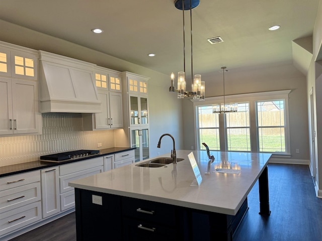 kitchen featuring visible vents, an island with sink, custom range hood, stainless steel gas stovetop, and a sink