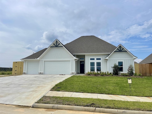 view of front facade with fence, a front lawn, concrete driveway, a garage, and board and batten siding