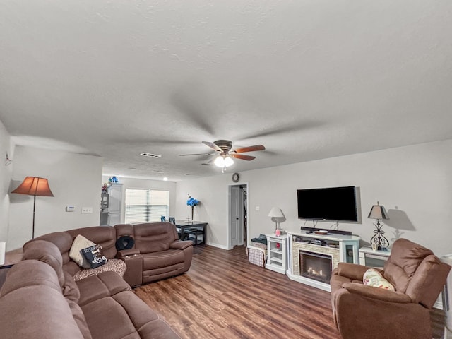 living room with hardwood / wood-style floors, a fireplace, ceiling fan, and a textured ceiling