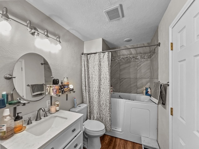 full bathroom with hardwood / wood-style floors, vanity, toilet, shower / bathtub combination with curtain, and a textured ceiling