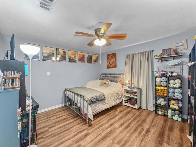 bedroom with hardwood / wood-style floors, ceiling fan, and a textured ceiling