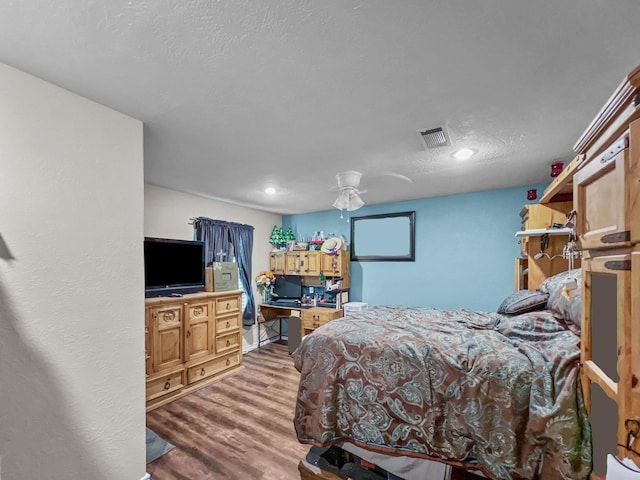 bedroom with ceiling fan, wood-type flooring, and a textured ceiling