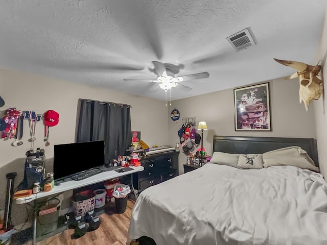 bedroom with hardwood / wood-style flooring, ceiling fan, and a textured ceiling