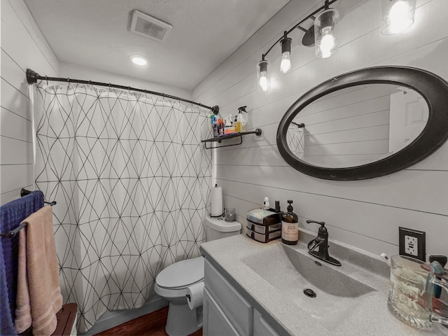 bathroom with a shower with curtain, wooden walls, vanity, and toilet