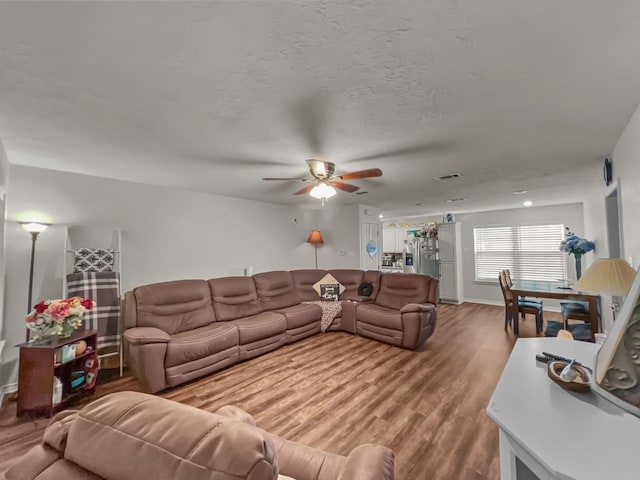 living room featuring ceiling fan, a textured ceiling, and hardwood / wood-style flooring