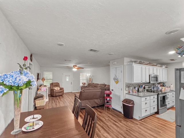 dining space featuring ceiling fan, a textured ceiling, and light hardwood / wood-style flooring