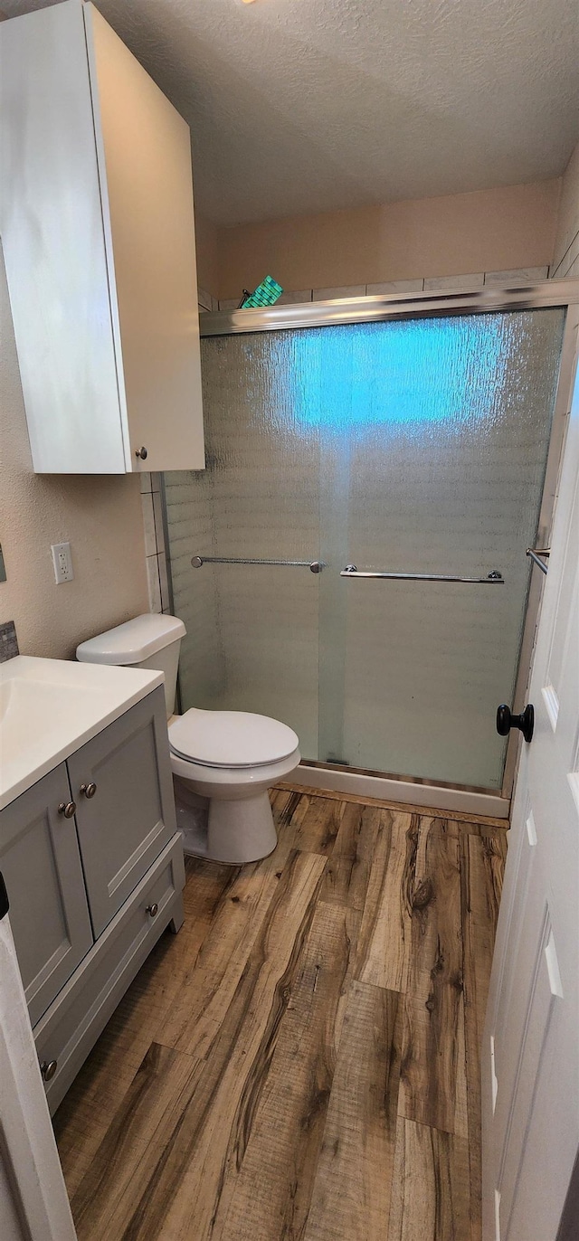 full bath with vanity, a stall shower, wood finished floors, and toilet