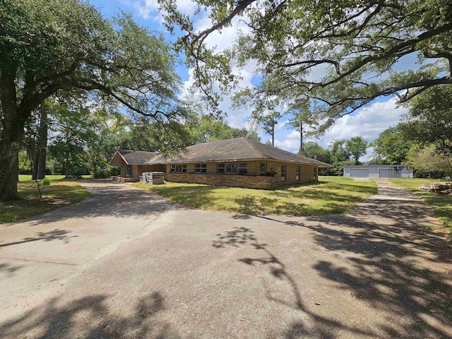 ranch-style house featuring a garage, an outdoor structure, and a front lawn