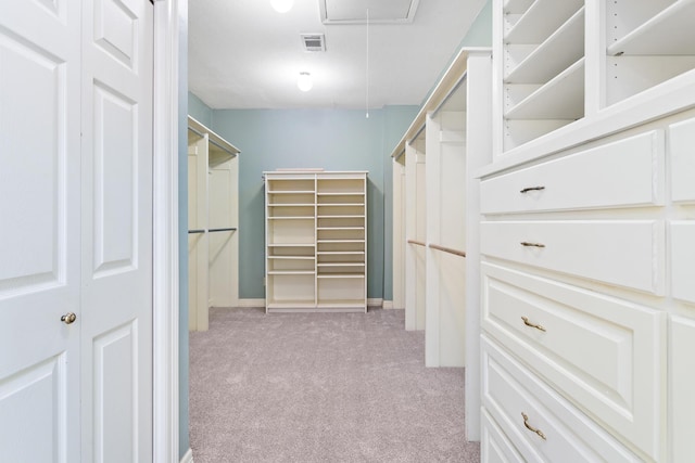 walk in closet featuring light carpet, visible vents, and attic access