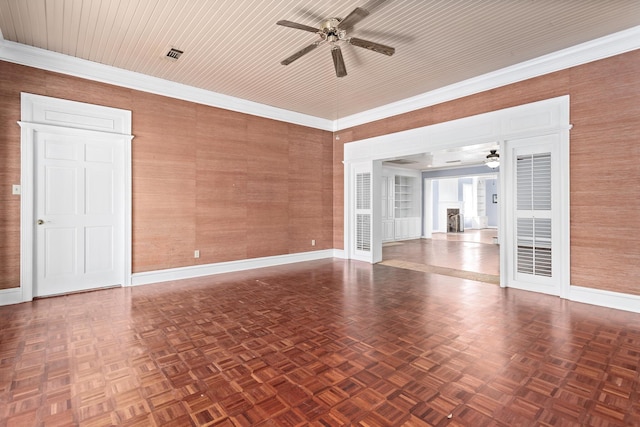 empty room with visible vents, baseboards, ornamental molding, a fireplace, and a ceiling fan