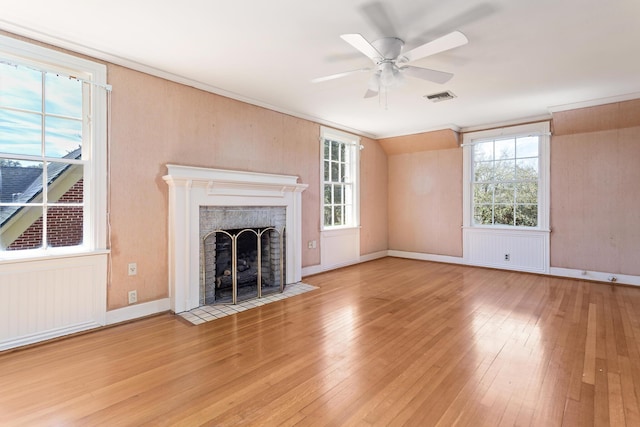 unfurnished living room with light wood finished floors, visible vents, ceiling fan, and a fireplace with flush hearth