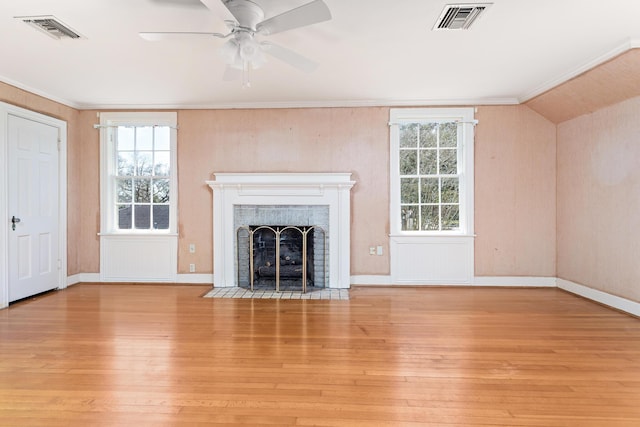 unfurnished living room with visible vents, a fireplace with flush hearth, a healthy amount of sunlight, and wood finished floors