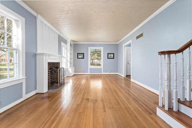 unfurnished living room with visible vents, light wood-style flooring, a fireplace, and plenty of natural light